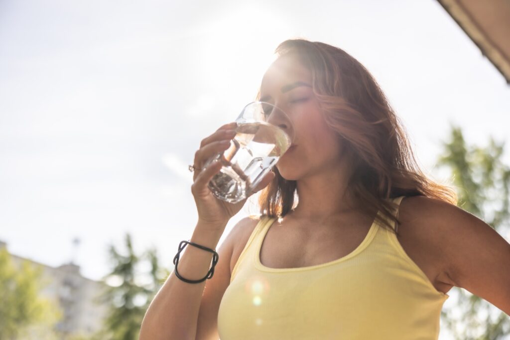 Mujer bebiendo agua, una medida importante para la prevención de cálculos renales.