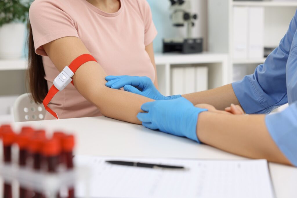 Extracción de sangre para biopsia líquida: Enfermera preparando el brazo de una paciente para extraer sangre, muestra necesaria para realizar una biopsia líquida.