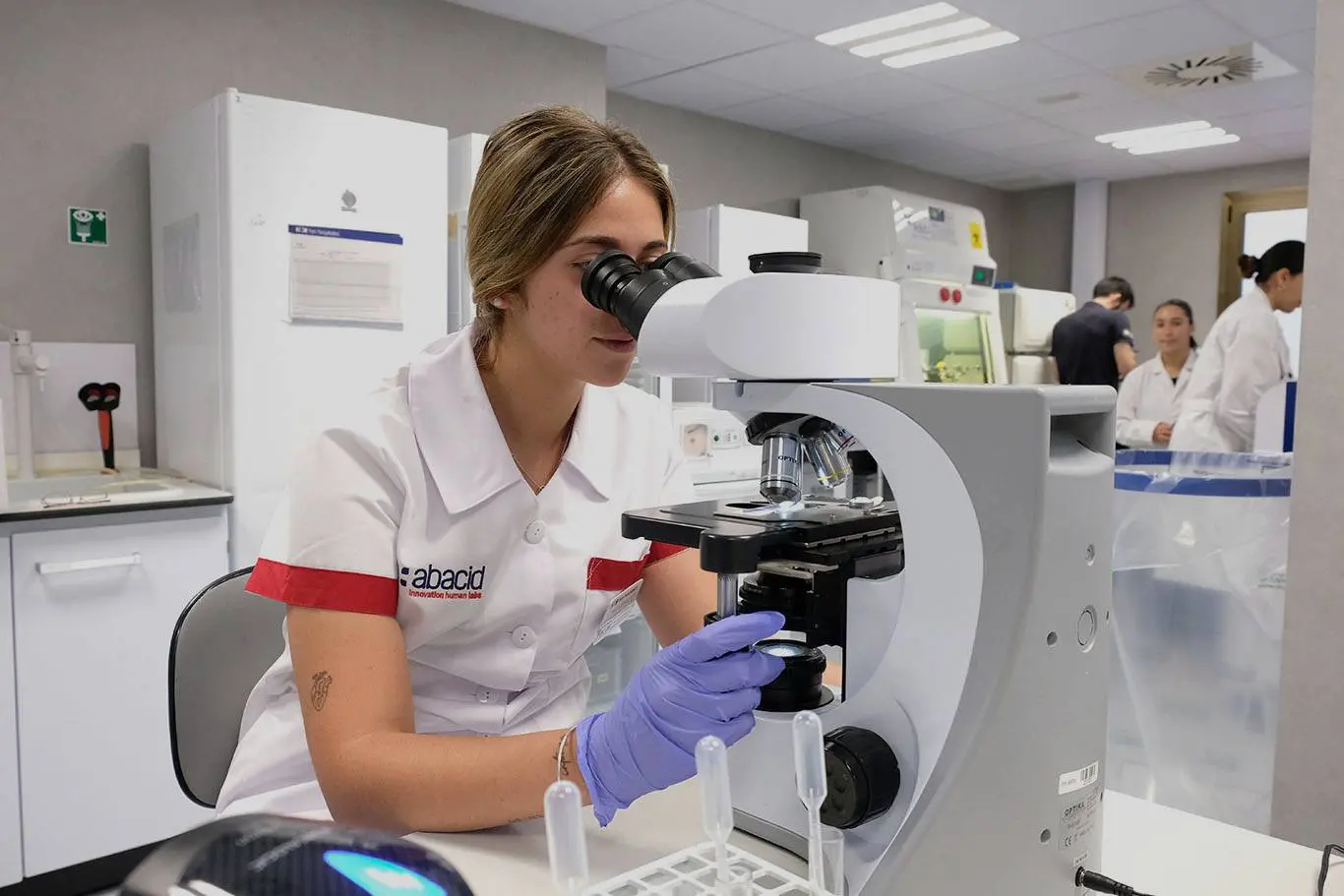 HM Abacid. Personal médico realizando pruebas con un microscopio.
