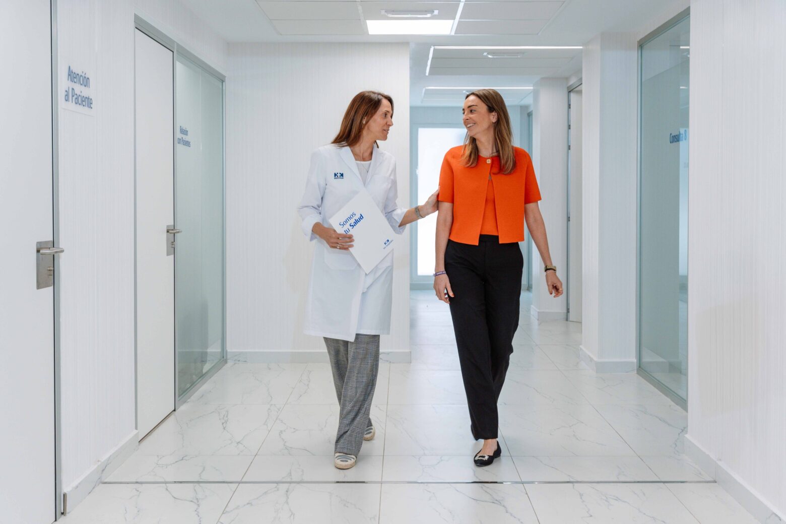Doctora y paciente andando por un pasillo de hospital
