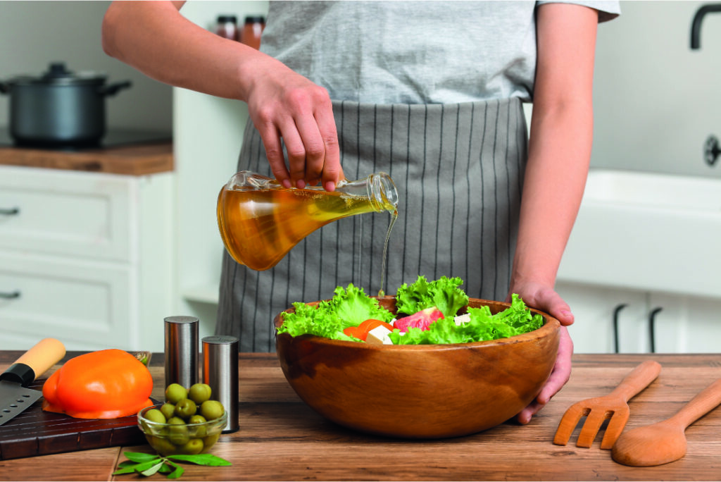 Mujer preparando una ensalada con aceite de oliva