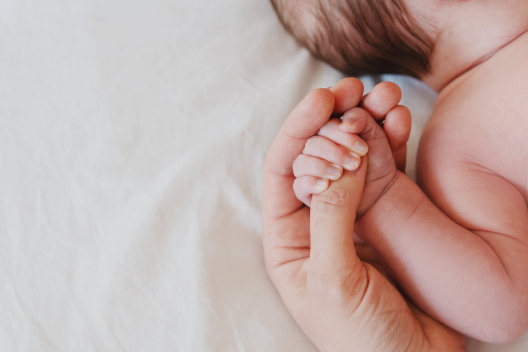 Bebé recién nacido sosteniendo el dedo de un adulto con su mano