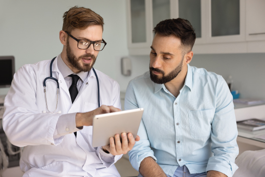 Hombre de 40 años con doctor en consulta consultando un informe médico