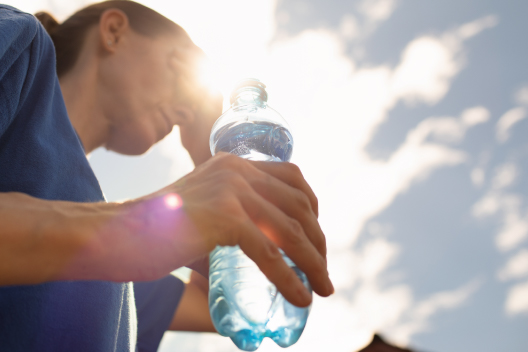 Mujer de 50 años en el exterior bebiendo agua en verano