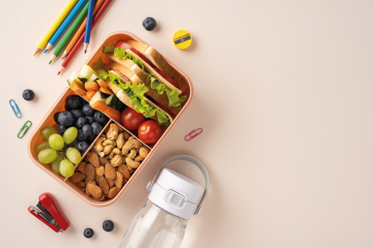 Tupper con comida saludable y material escolar