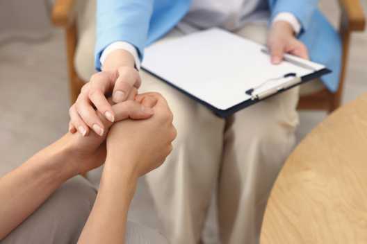 Psicóloga sosteniendo la mano de una paciente para brindar apoyo y confianza durante una consulta de terapia.