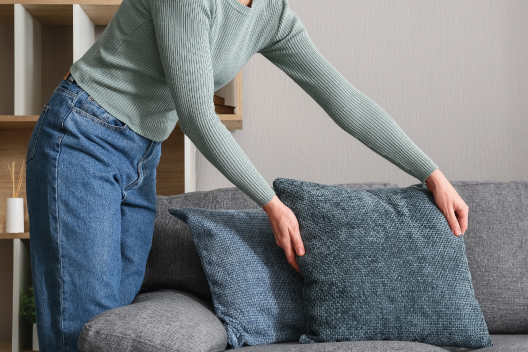 Mujer acomodando cojines en un sofá de forma meticulosa, representando las compulsiones de orden y simetría en el TOC.