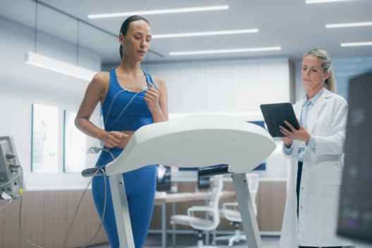 Atleta realizando una prueba de esfuerzo en cinta de correr mientras una médica monitoriza su actividad cardíaca