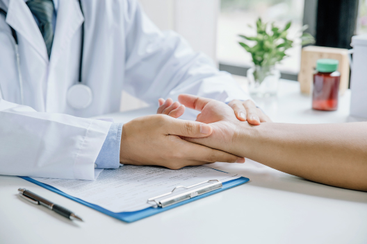 Médico palpando y examinando la articulación de la mano de un paciente para diagnosticar rizartrosis del pulgar.