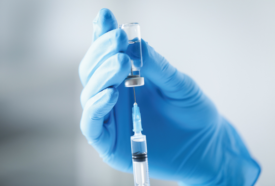Mano con guante médico preparando una jeringa con aguja desde un vial de medicación, representando la belonefobia o miedo a las inyecciones.