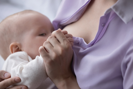 Primer plano de un bebé recién nacido mamando del pecho de su madre con un agarre correcto durante la lactancia.