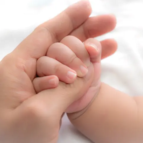 Mano de adulto y de bebé entrelazadas