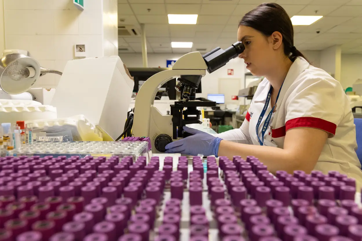 Personal sanitario revisa muestras analíticas en un microscopio.